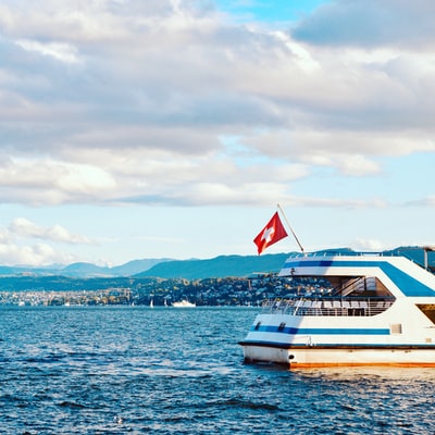 In the daytime, in the cloudy sky, white and blue boat is sailing on the sea
